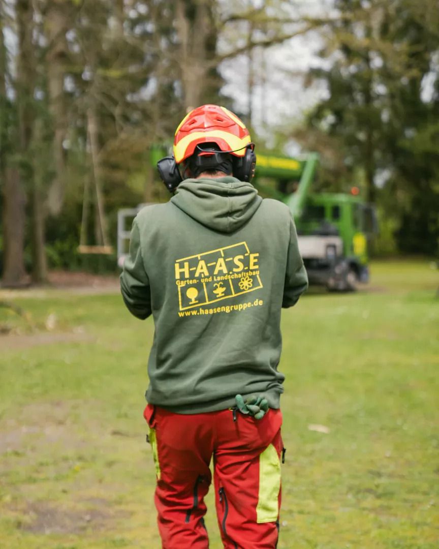 Ein Mitarbeiter der einen Pullover von Grünpflege - Grünwert Lüneburger-Heide Hamburg GmbH - Bergen trägt