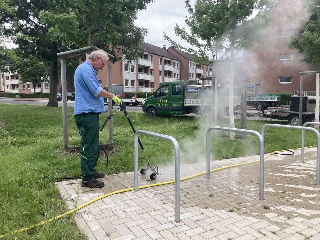 Ein Mitarbeiter reinigt eine Graufläche mit einem Heißwassergerät